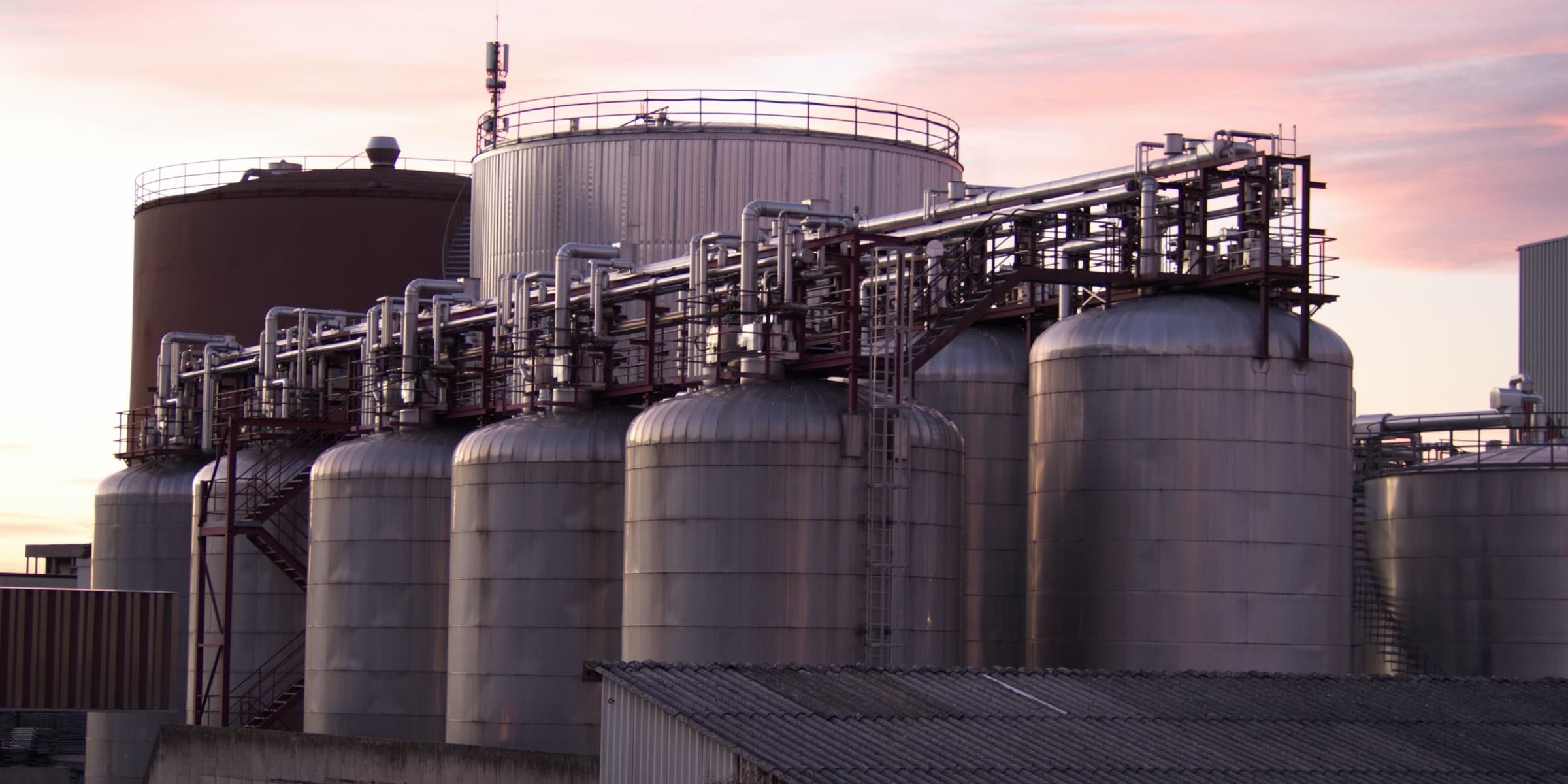 Stainless steel storage tanks and pipes at sunset